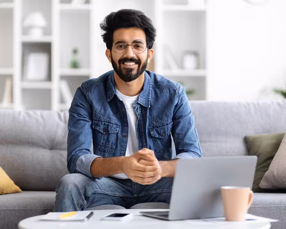 Person sitting with laptop on couch.
